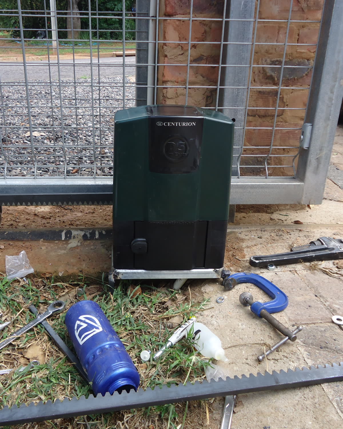 Motor de portão recém-instalado, com a cremalheira e as ferramentas da instalação no chão